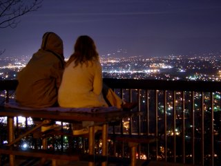 A couple sits on a picnic table, looking out over the city of Roanoke.