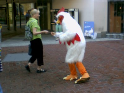 A man in a rooster costume hands out literature at Dupont Circle station