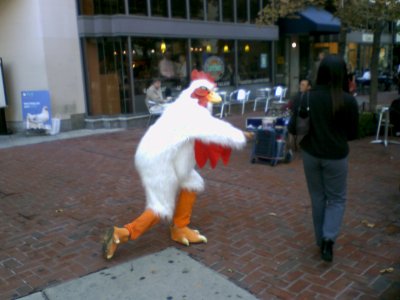 A man in a rooster costume hands out literature at Dupont Circle station