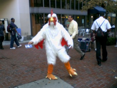 A man in a rooster costume hands out literature at Dupont Circle station