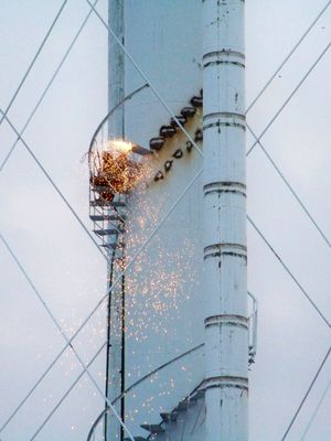 It appears that this man is using a torch to cut the steps off the center of the water tower next to Glenmont station.