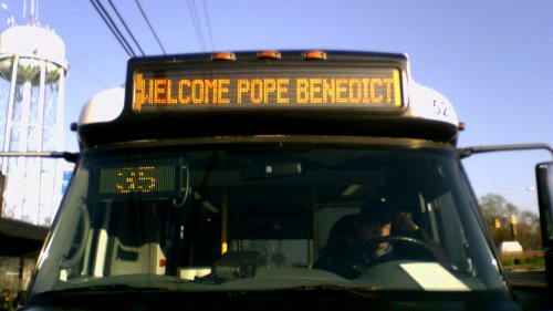 Ride On cutaway displaying "Welcome Pope Benedict" on its sign