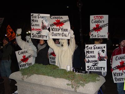 Polar bears and humans alike hold signs recommending strongly against extracting oil from the tar sands.