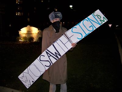 Holding up a sign for yousawthesign.com, which is an anti-Scientology site, similar to youfoundthecard.com.