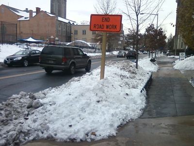 Snow piled around a road construction sign.