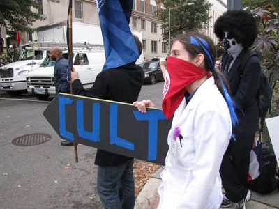 An Anon holds a sign that says "CULT" and points it at the Ideal Org. For the record, many of the residents of this end of Dupont Circle that we spoke to are embarrassed for the neighborhood that Scientology has moved in.