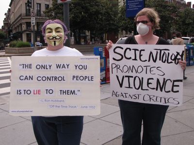 Purple Hair Anon and an Anon from Australia carry signs on the triangle.