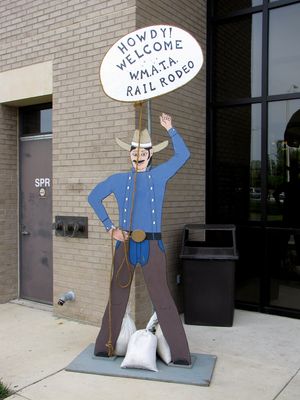 Wooden cowboy cutouts outside the shops building, welcoming people to the Rail Rodeo.