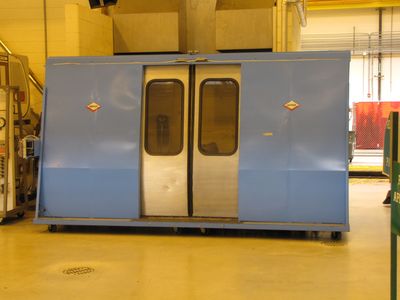 Mockup of train doors, presumably part of the competition. In the extreme left of the photo, if you look carefully, you can see two mockup rail cars stacked at left. These are presumably also part of the competition, and they had car numbers: 5000 and 5001. In other words, CAFs. However, the illustration of a car end on these cars looked very Rohr-like. Details, details...