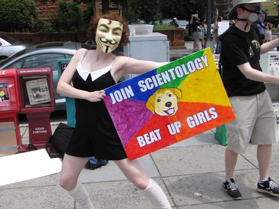 Beret demonstrates this point with her "Join Scientology, beat up girls" sign.