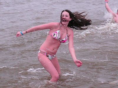 A girl wearing nothing but a bikini stands in the water.