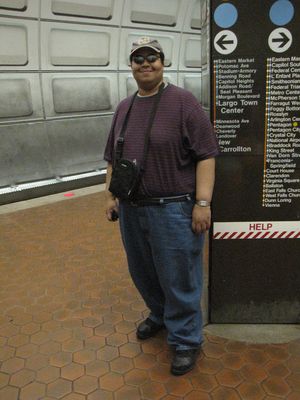 I photographed Matthew in front of one of the platform pylons in Eastern Market. He wanted to wear his sunglasses for the photo, as seen at left. I was like, "Why? There's no sun in here." But he insisted, so we shot it that way. Then I made him switch to his regular glasses, and got him again.