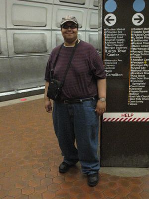 I photographed Matthew in front of one of the platform pylons in Eastern Market. He wanted to wear his sunglasses for the photo, as seen at left. I was like, "Why? There's no sun in here." But he insisted, so we shot it that way. Then I made him switch to his regular glasses, and got him again.