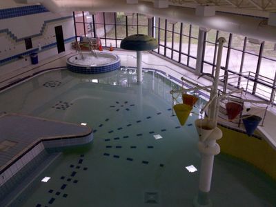 The "leisure pool" (read: kiddie pool) area. This pool is three feet deep at its deepest, and water is normally flowing out of the top of the mushroom structure towards the back, and water fills the buckets in the right of the photo. The buckets tip over and dump their contents when they become full. There's also a small water slide that's mostly out of frame, but you can see part of it behind the buckets. One of the two "hydrotherapy pools" (read: hot tub) is visible in the background.