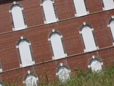 Boarded up windows on the front side of the north building. Why they bothered to paint the board-up is beyond me, but paint it they did.