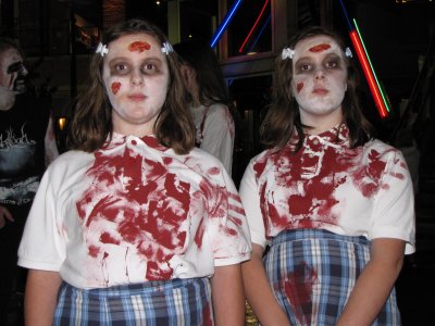 Two children dressed as zombies, looking far too wholesome to be covered in blood.  And the blank expressions add to the scary effect.