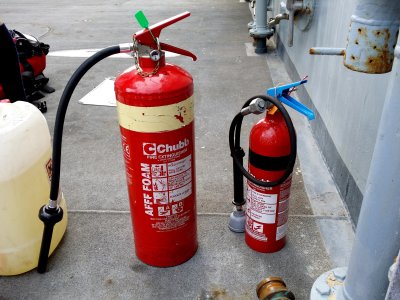 Two Chubb-brand fire extinguishers. The larger extinguisher on the left uses foam, while the smaller extinguisher uses carbon dioxide.