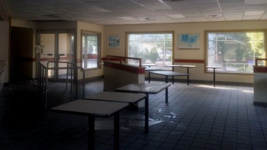 Dining room, facing the main entrance. Note the exit sign and emergency light dangling from the ceiling via a conduit.