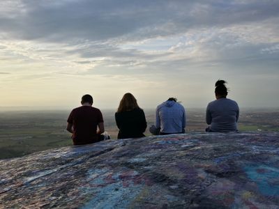 Four teens sitting on High Rock, all checking their phones.