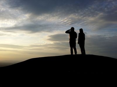 Two people stand on High Rock, looking out over the landscape. View facing west.