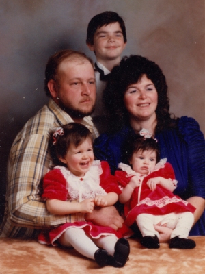 Family portrait, likely from the 1980s. As far as I can tell from various things I've found, the man with the beard who looks positively miserable is Scott Alan Bauer, the wife's name is Barbara (based on the child support document), I couldn't find the boy's name, and the two girls' names are Andrea and Stacie (based on notes on the photos, though I don't know who is who).