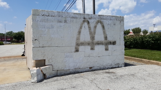 McDonald's labelscar on the dumpster enclosure. Guessing that this will be painted out as well.