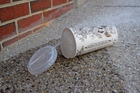 A discarded Chipotle cup filled with a frozen beverage.