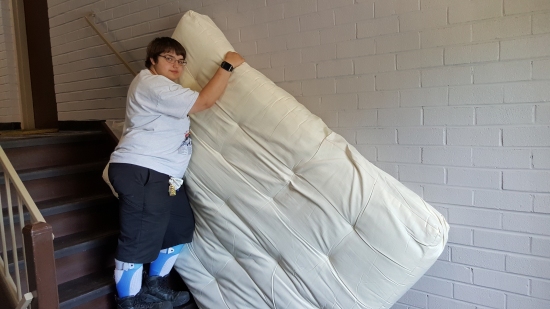 Elyse holds an end of the mattress on the stairs while I take a photo.