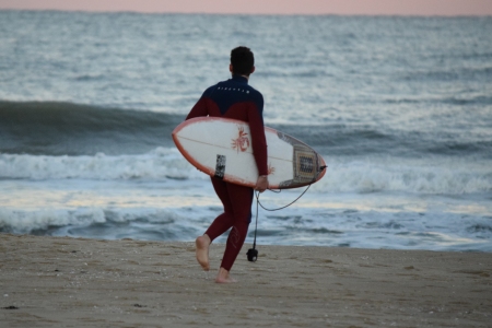 Guy in a wetsuit, about to go surfing.