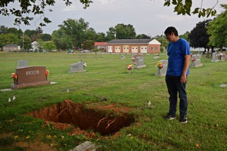 Aaron stands next to an open grave, contemplating life.