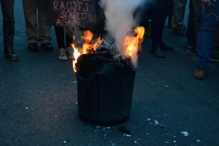 The trash can, buckling as its contents burn.