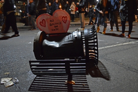 Another overturned trash can near Franklin Square, with a sign stuck in it. The interior container is the same as the one that was set on fire.