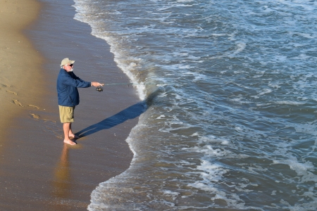 A man goes fishing in the ocean.  Was surprised that he was walking around barefoot!