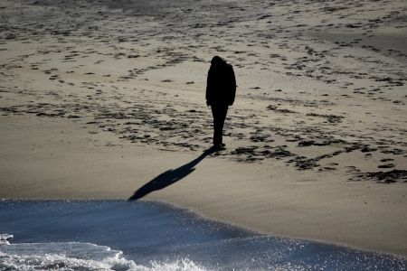 A person walks along the beach, south of the fishing pier.