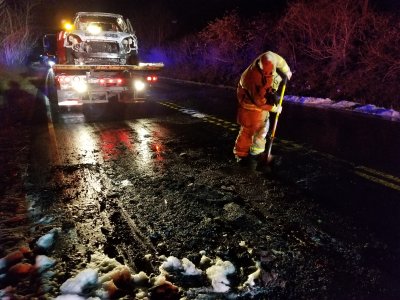 A firefighter uses a shovel to scrape the debris from the fire off of the road, so that the road could reopen.