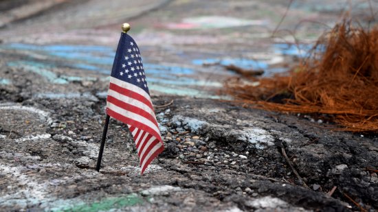 An American flag, stuck into one of the cracks in the old road.