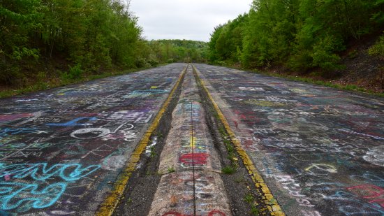 Looking south near the bottom of the Graffiti Highway.  In the distance is the end of the abandoned section.  The active roadway is just over the ridge.
