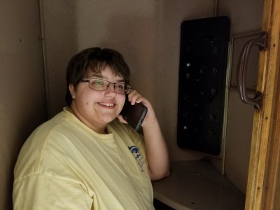 Elyse sits in a now-obsolete phone booth with her cell phone.