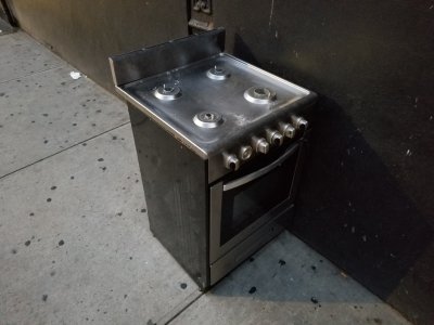 A gas stove sitting on the sidewalk