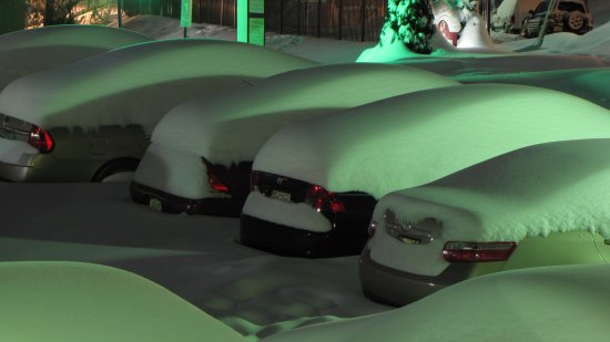 Cars parked along the side spaces, with a significant amount of snow accumulation, though nowhere near as much as the cars alongside the building got.