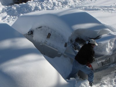 One of my neighbors clears a huge chunk of snow off of the trunk of his car.