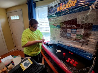 Elyse gets to work unwrapping the arcade machine.