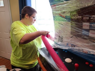 Elyse gets to work unwrapping the arcade machine.