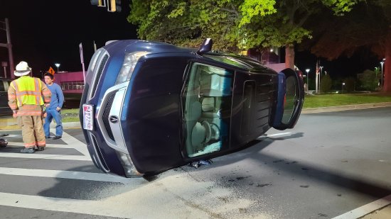 The Acura, on its side, after the driver crawled out through the back hatch.  The man in the blue is not the driver, but rather, he is an off-duty firefighter who happened to pass by and rendered some assistance, particularly in helping the driver get out.