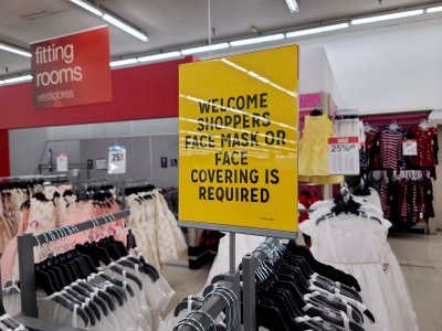 Face mask signage in the clothing section.  The fitting rooms, visible in the background, were closed because of coronavirus.