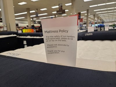 Signs describing their "mattress policy", prohibiting customers from sitting on the beds, because coronavirus.