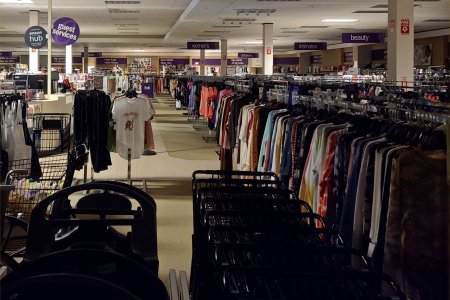 Long racks of clothes on the right side of the store.  Long racks of clothes like that are a typical arrangement for an off-price store.