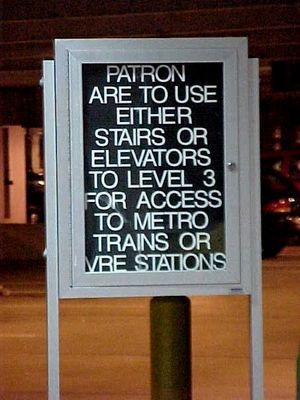 Signs in the parking garage at Franconia-Springfield.  One sign explains how to get to the station from the garage, and the other has been modified by a prankster to endorse the passing of gas while on television.