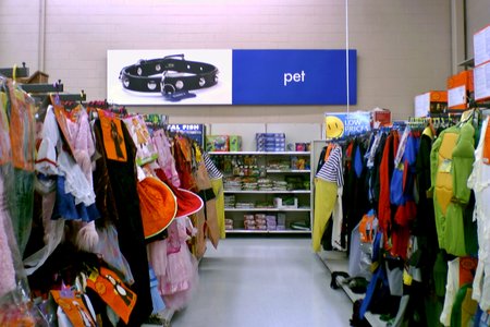 Wall signage for the pet department, with racks of Halloween costumes in front.
