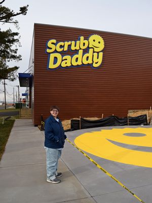 Elyse poses with the Scrub Daddy sign on the building.